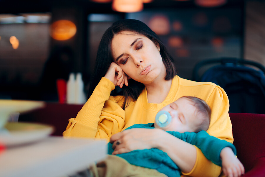 tired mother holding infant both sleeping sitting up
