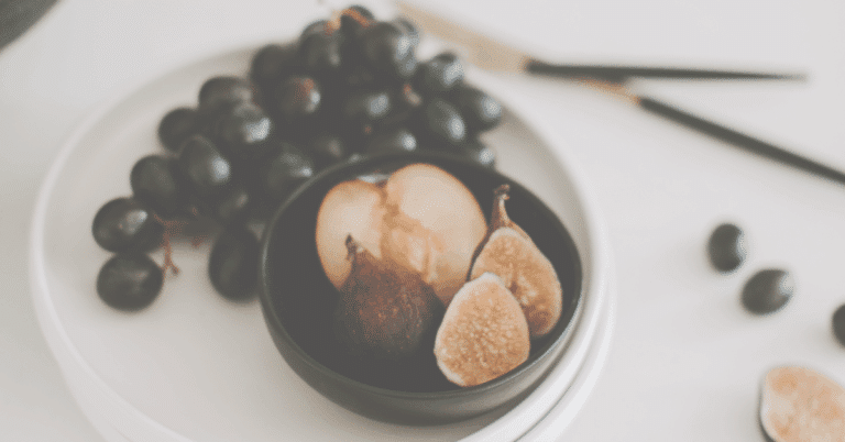 Grapes, Plum cut in half and fresh figs on plate