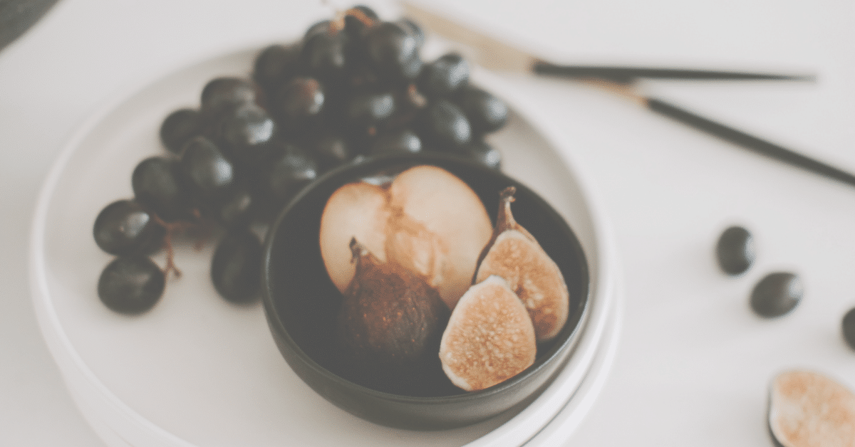 Grapes, Plum cut in half and fresh figs on plate